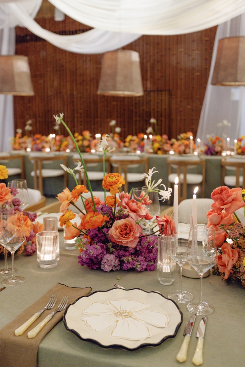 Place setting with a hand-painted flower charger, amber candles and a low centerpiece