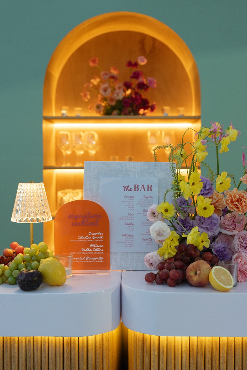 Cocktail bar with arched display, signature drink menu and abundant tropical florals