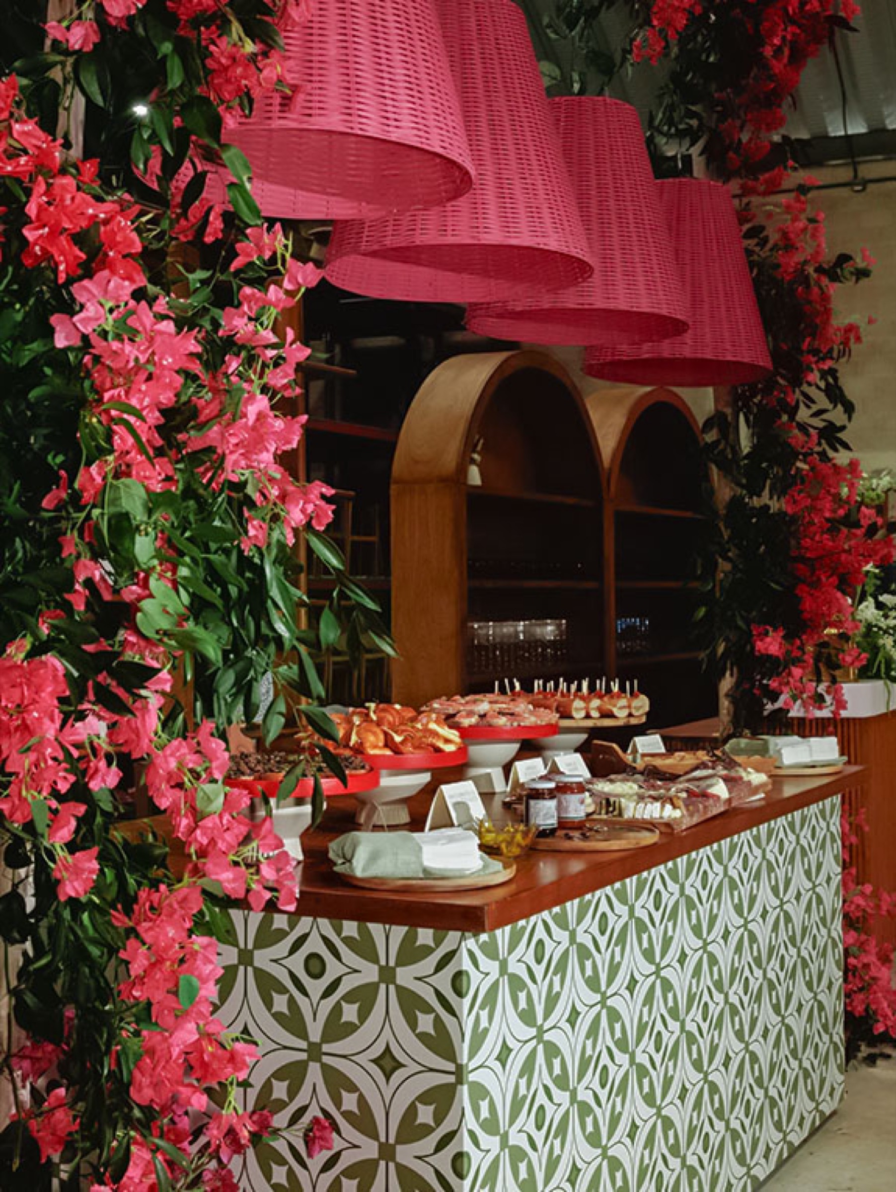 Custom bar with green-and-white talavera tile, oversized pink rattan pendant lamps and bougainvillea