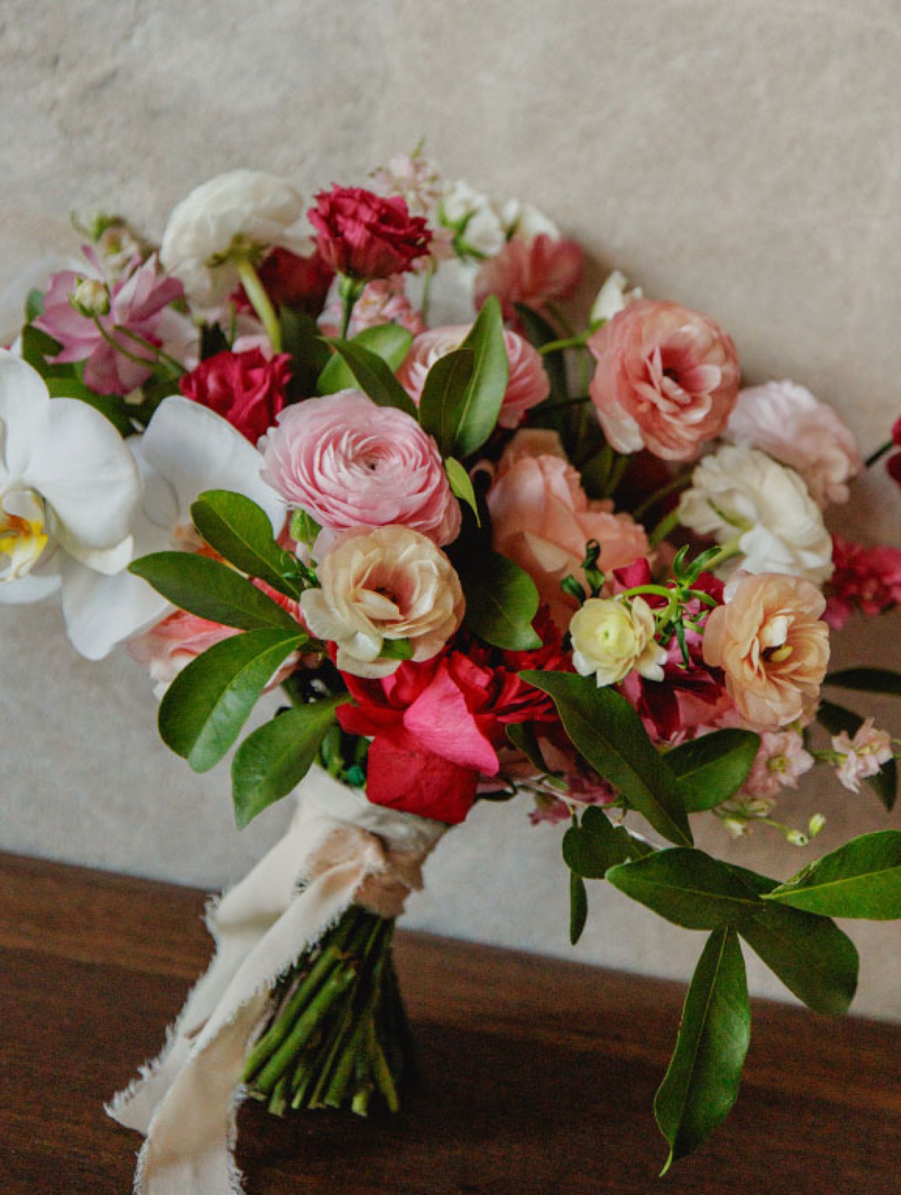 Bridal bouquet of pink and white garden roses, ranunculus and orchids with silk ribbon